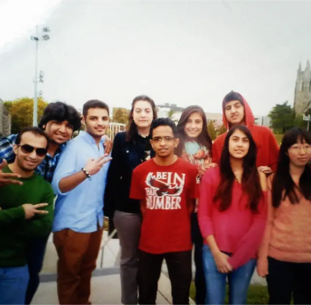 Maria, an English teacher, standing with her students outdoors, smiling for a group photo.